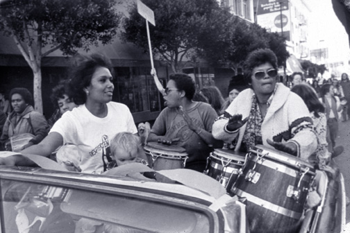 women drumming in a convertible during a victory parade