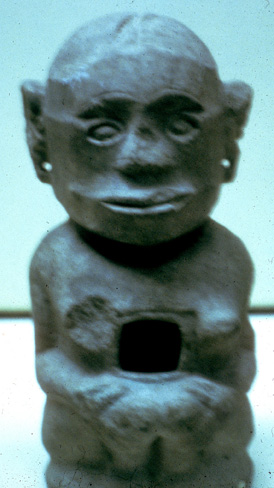 short stone sculpture with big head and vulva, and large hollow between breasts and waist