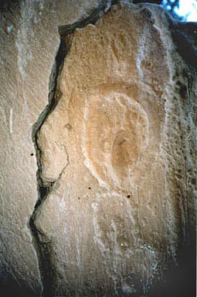 row of vulvas deeply engraved into rock wall
