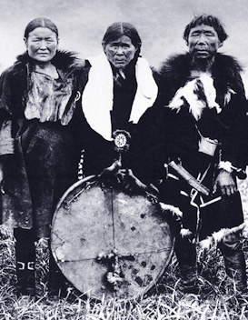 older woman holding drum resting on ground